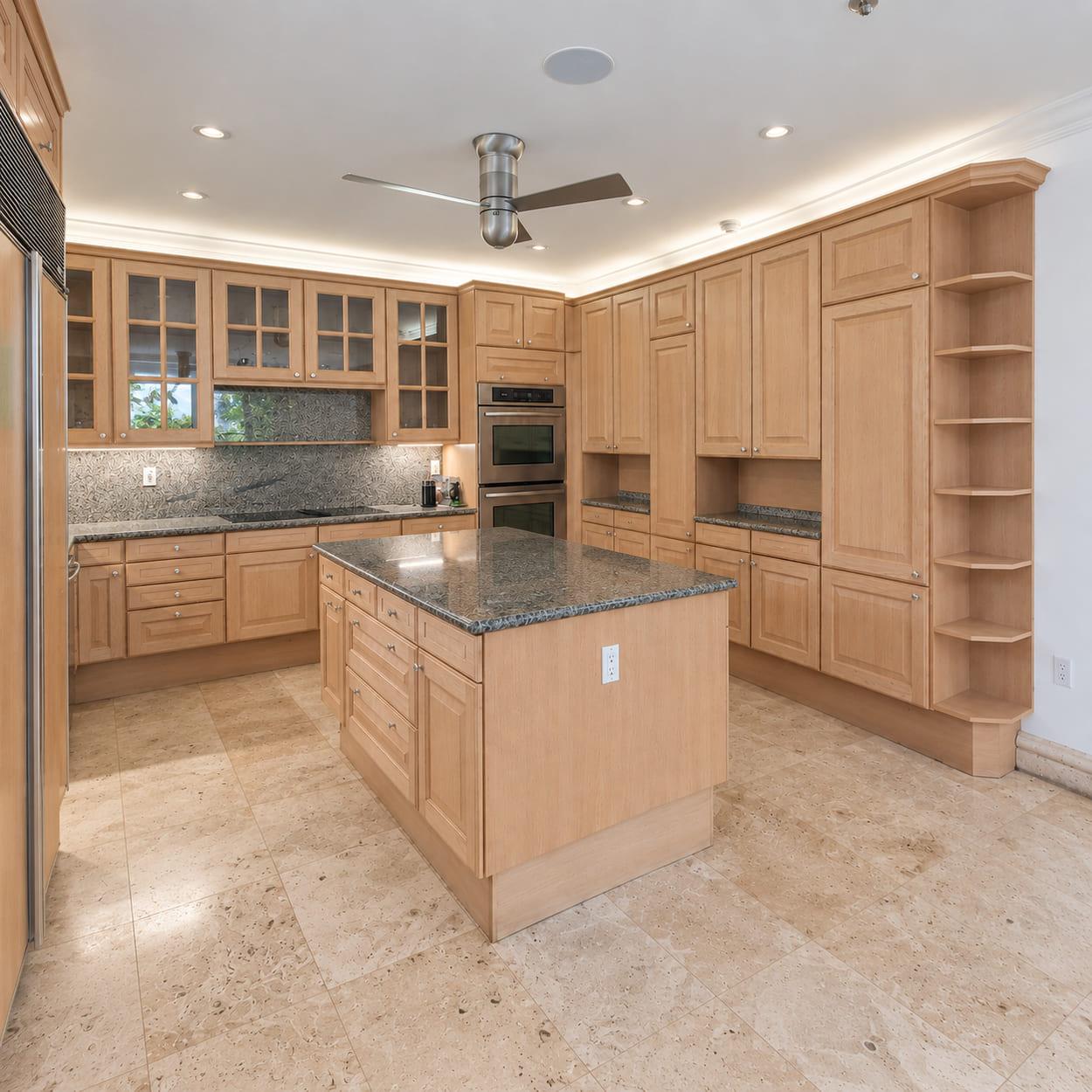 The old oak island under speckled granite, with wall ovens behind it