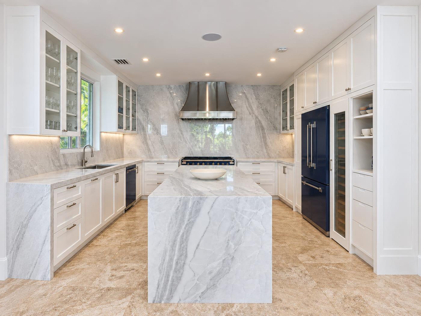 The same kitchen finished: white inset cabinetry, a marble slab wall and a cobalt range