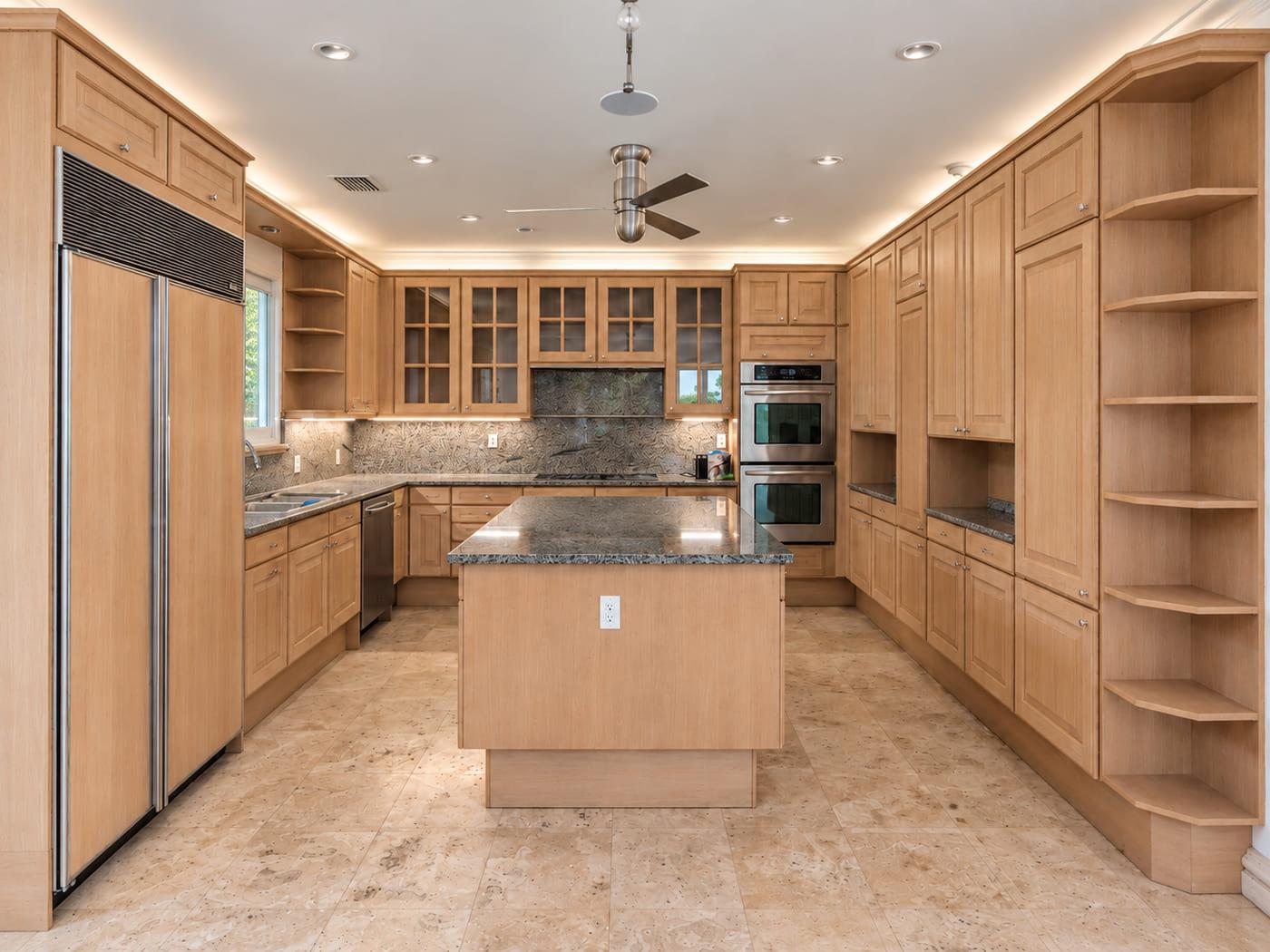 The kitchen as received: oak raised-panel cabinets, granite counters and a ceiling fan