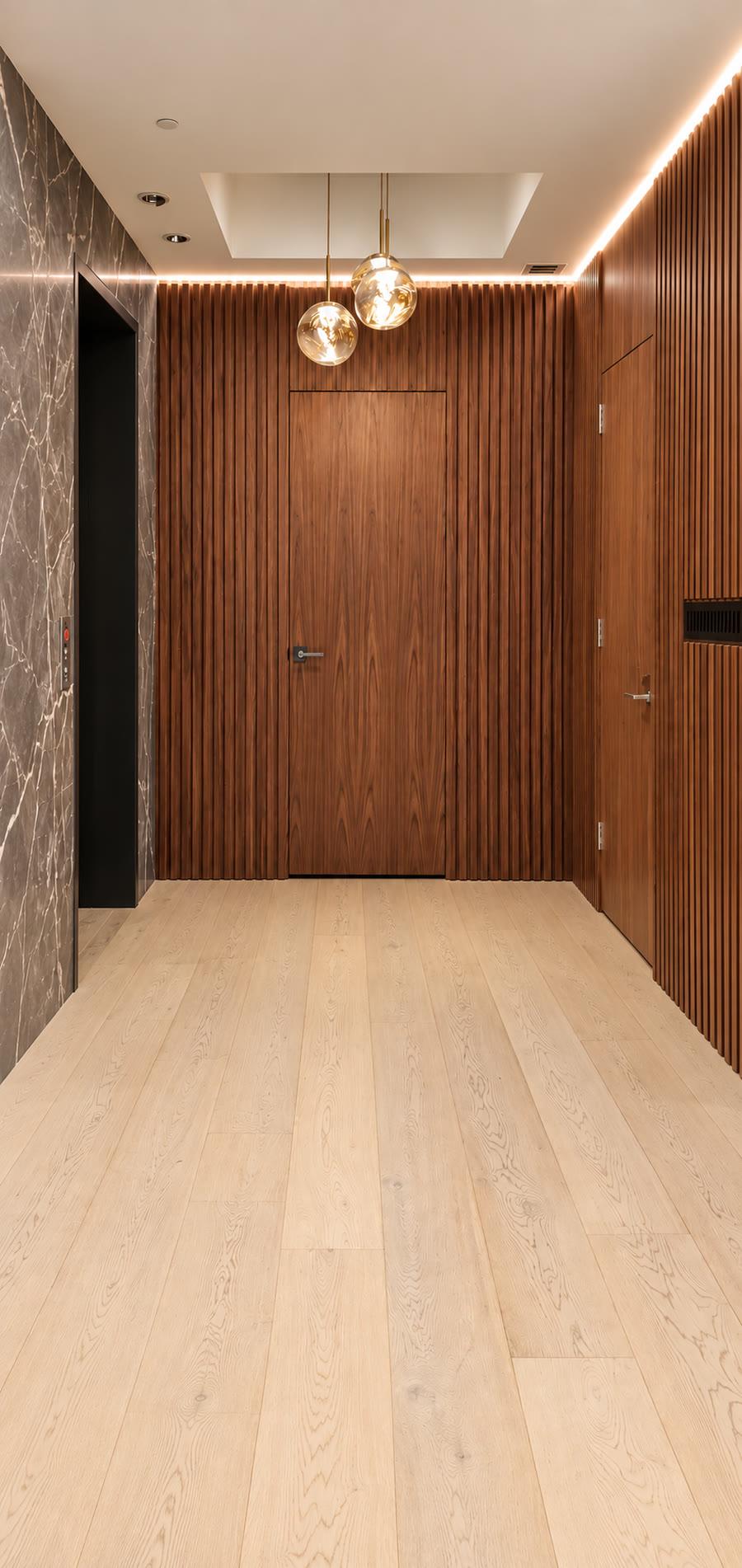 Lift lobby in grey marble and walnut slats with amber pendants