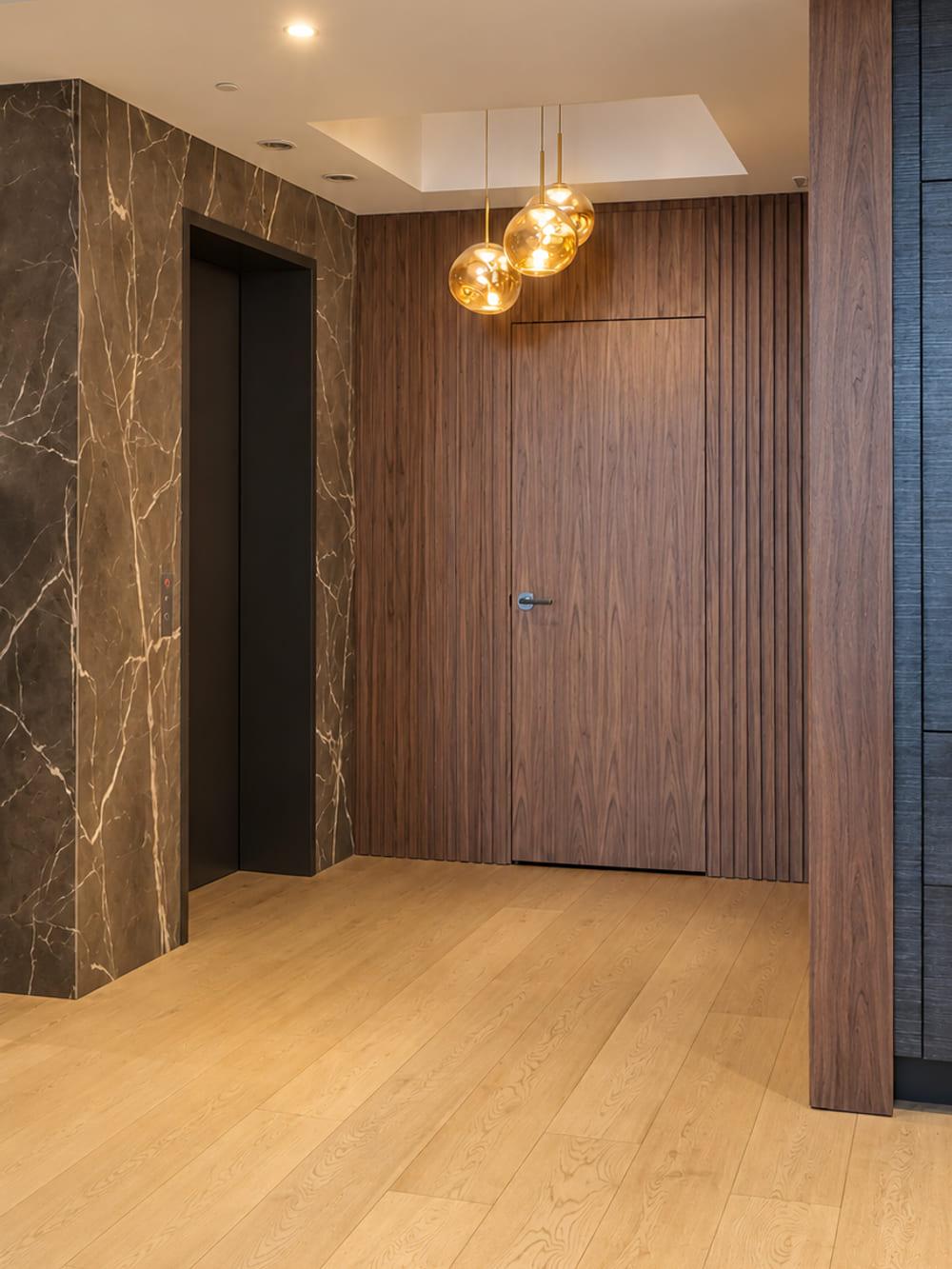 The entrance finished in walnut and marble with amber glass pendants