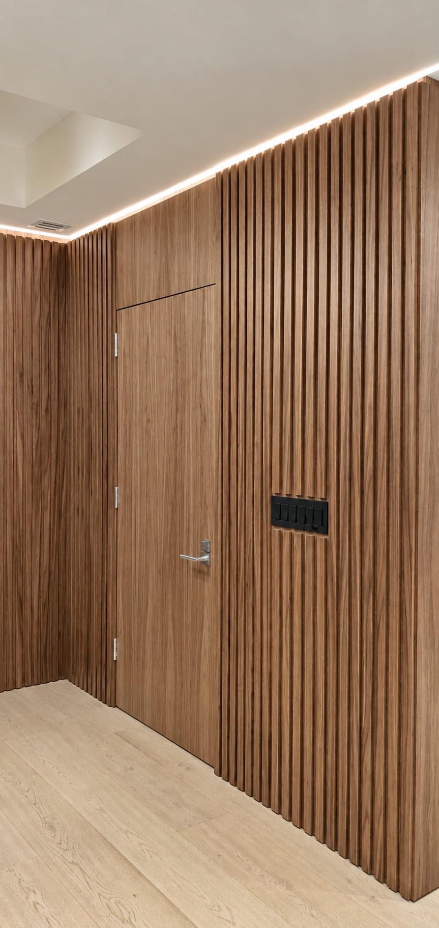 Walnut slat wall turning a corner past a flush door and a switch plate