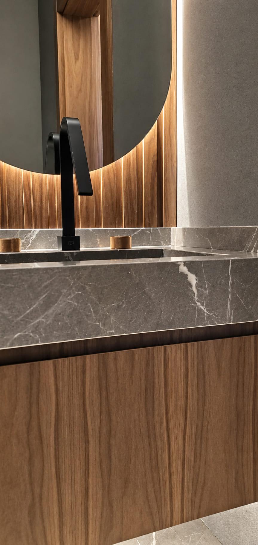 Basin carved from a honed stone slab with a black tap
