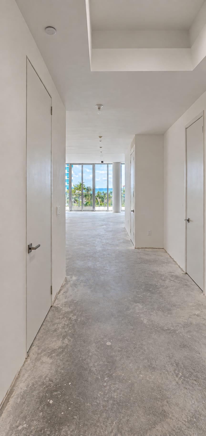 The corridor as received: bare concrete floor, plain doors and taped walls