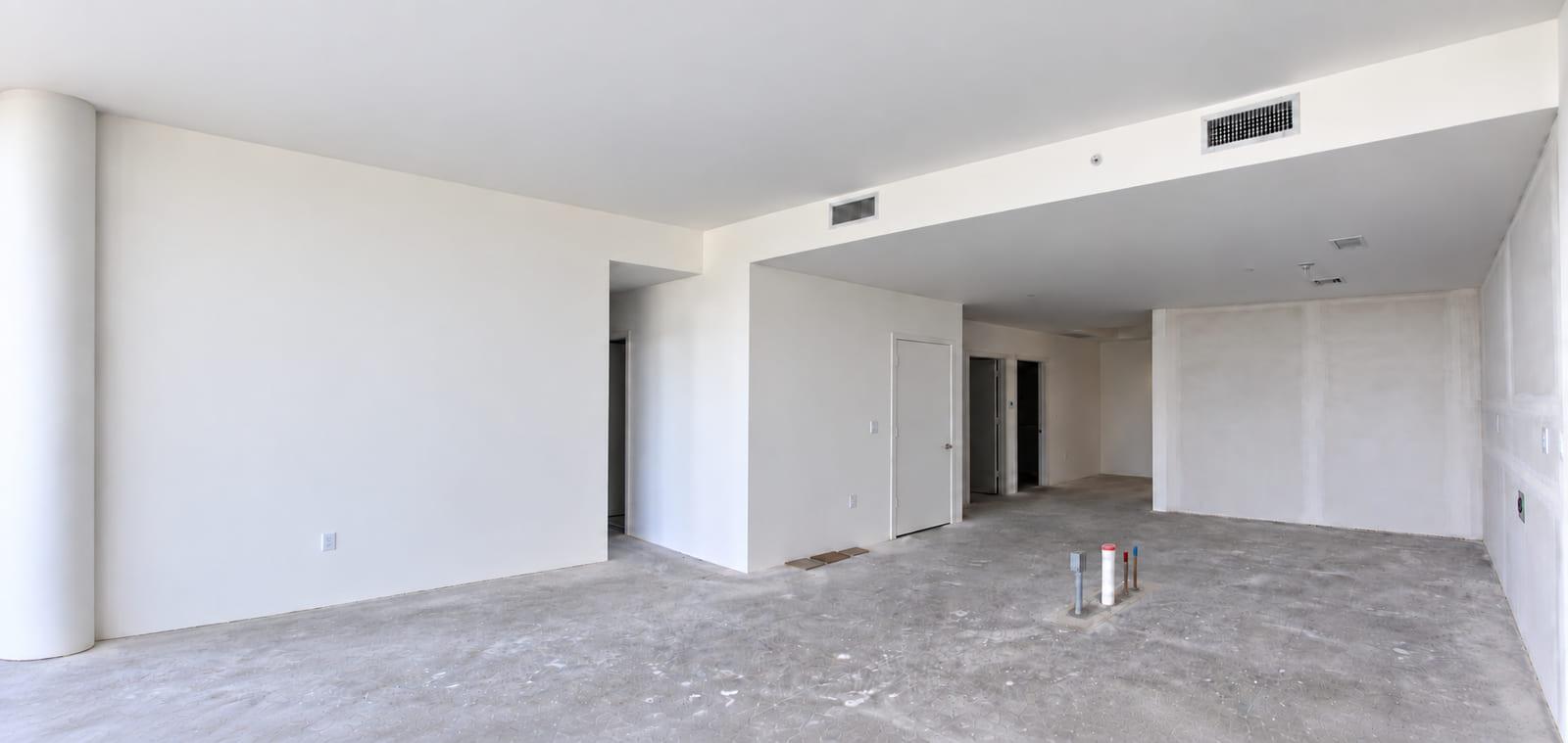 The living floor as received: bare slab, taped drywall and an unfinished drop ceiling