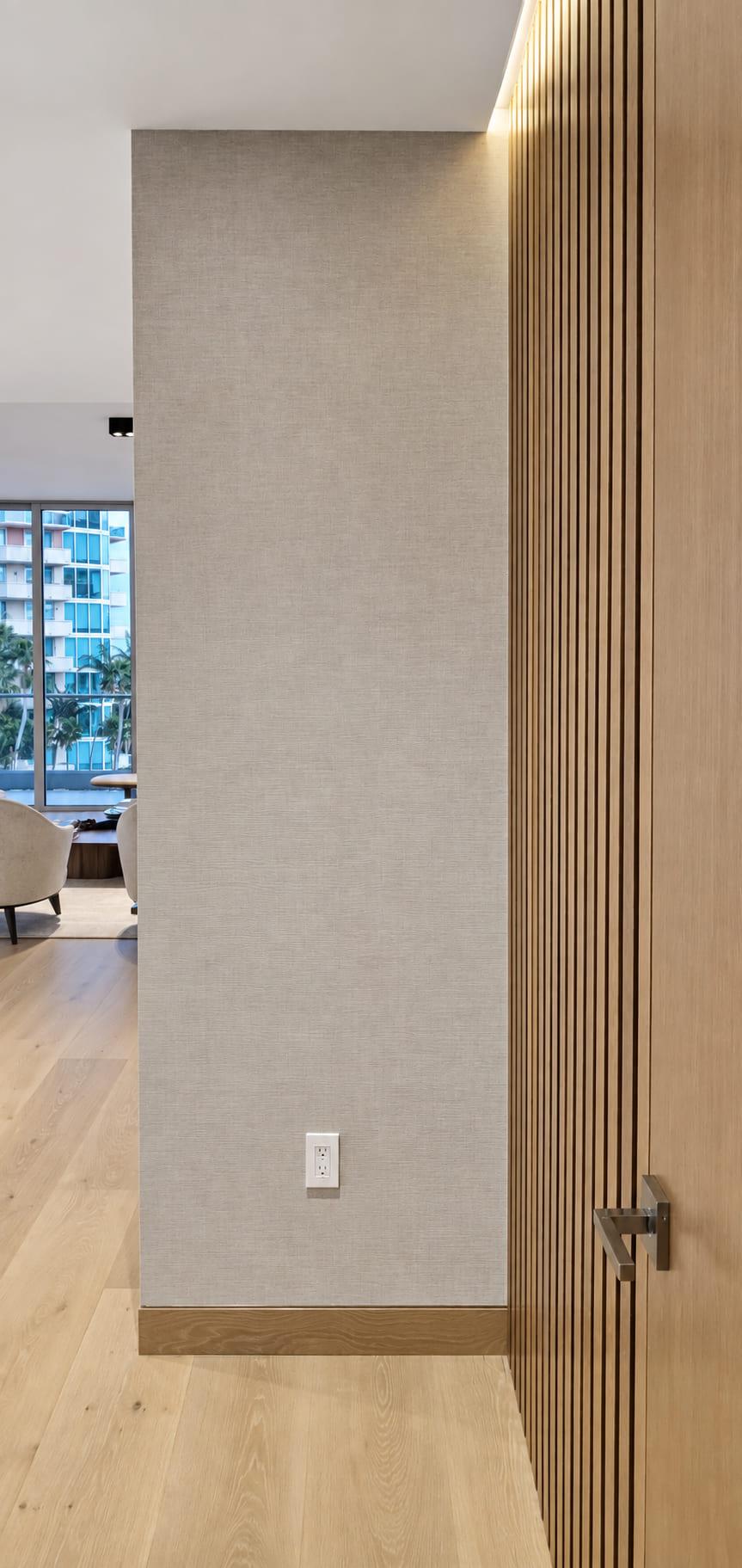 A linen-finish wall returning into a walnut slat run above an oak skirting